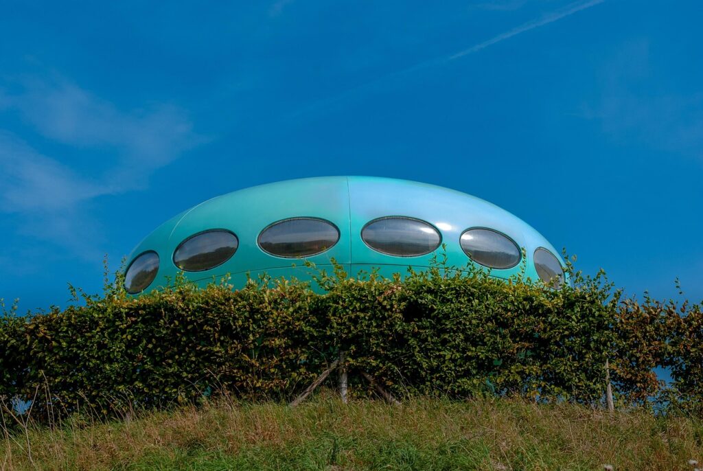 Casa redonda futurista azul semelhante a um OVNI em colina gramada