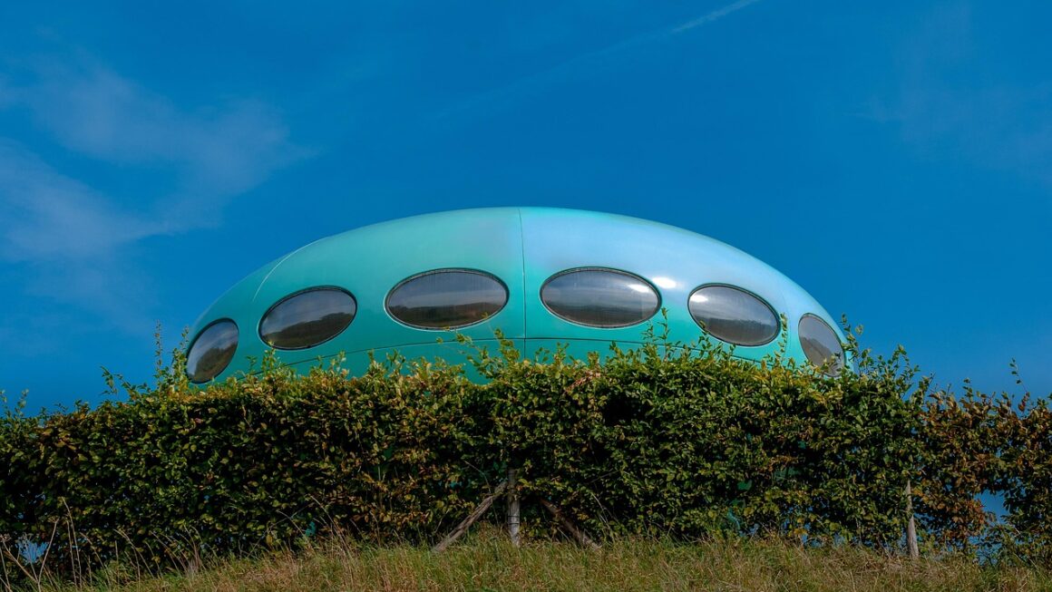 Casa redonda futurista azul semelhante a um OVNI em colina gramada